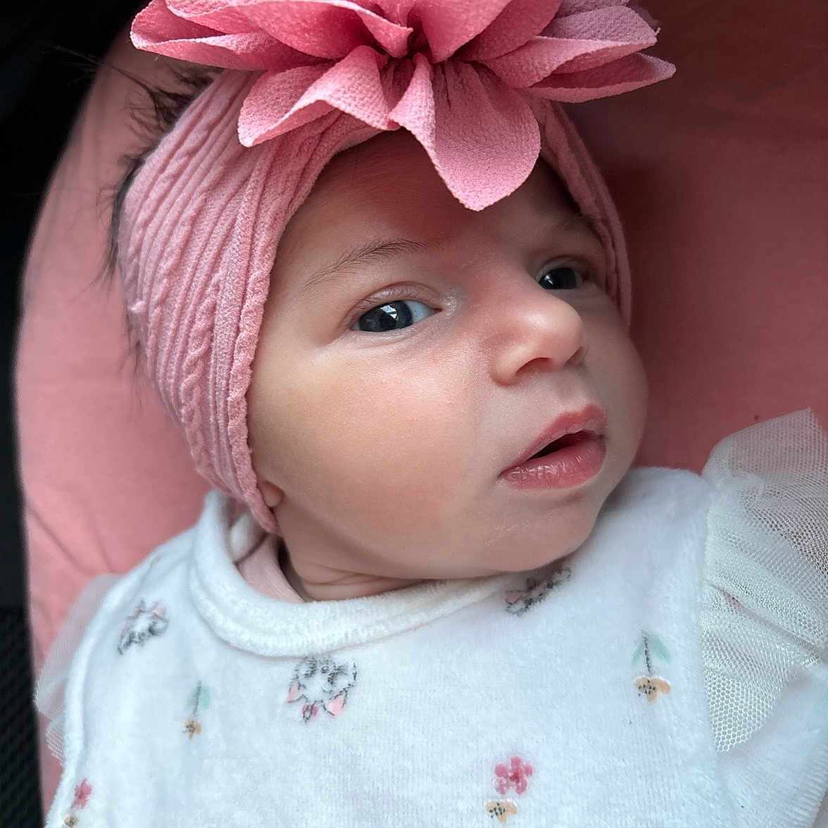Sierra a rejoint le concours — aidez-le/la à gagner de superbes lots ! adorable, baby, child, close_up, clothing_pattern, cute, expression, eyes, face, headband, infant, newborn, person, pink_flower, portrait, skin, soft_texture, tulle_sleeve, white_clothing, young