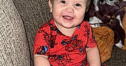 Liam is registered to the contest to win money with this photo: baby, blanket, cat, child, clothing, couch, family, hand, happy, home, indoor, infant, pacifier, pet, portrait, red_outfit, sitting, smiling, sofa, superhero