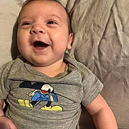 Liam joined the competition — help win amazing prizes! baby, infant, smile, laugh, mickey_mouse, tshirt, clothing, bed, fabric, wrinkles, skin, cute, happy, child, person, indoors, young, casual, lying_down, playful