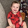 adult_hand, baby, blanket, cat, child, closeup, couch, family, happy, home, indoor, infant, pacifier, pet, portrait, red_outfit, sitting, smiling, sofa, superhero_costume