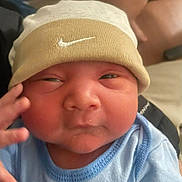 Liam joined the competition — help win amazing prizes! baby, newborn, infant, beanie, hat, nike_logo, face, cheeks, hand, eyes, onesie, blue_clothing, close_up, portrait, indoor, sleepy, soft_skin, cute, newborn_hood, expression
