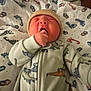 baby, newborn, infant, yawning, beanie, hand_in_mouth, onesie, dinosaur_print, footprint_blanket, crib, bedding, hospital_bassinet, sleeping, cute, portrait, chubby_cheeks, pajamas, soft_texture, blanket, tiny_fingers