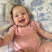 River-Lavinia joined the competition — help win amazing prizes! arm, baby, blue_print, child, closeup, cute, expression, face, happy, indoors, infant, joy, legs, pillow, pink_onesie, portrait, sitting, skin, smile, white_background