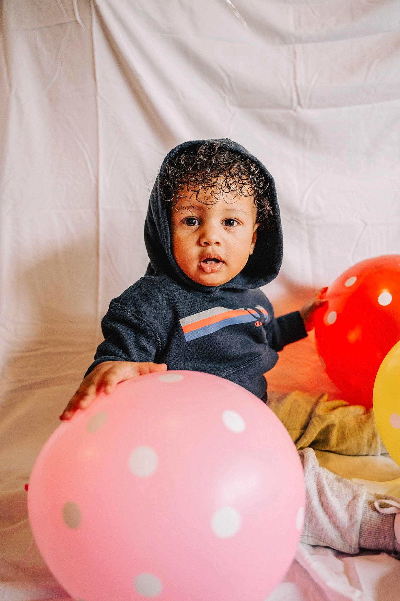 Amir joined the competition — help win amazing prizes! baby, ball, balloon, black_hair, child, fun, happy, outerwear, party, person, photography, pink, play, red, room, sitting, smile, toddler, yellow