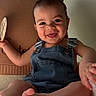 baby, smiling, denim_overalls, child, infant, happy, cute, portrait, sitting, hand, foot, cozy, blanket, indoors, young_child, face, skin, expression, milestone, text_overlay