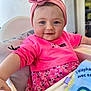 baby, child, high_chair, pink_clothing, flower_headband, smiling, blue_eyes, cute, infant, portrait, indoor, happy, person, toddler, clothing, seat, feeding_chair, headwear, cute_outfit, closeup