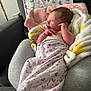 newborn, baby, swaddle, pacifier, blanket, cushion, sofa, footprint_pattern, heart_pattern, indoor, infant, resting, comfort, soft_toys, fabric, child, person, portrait, relaxation, cute