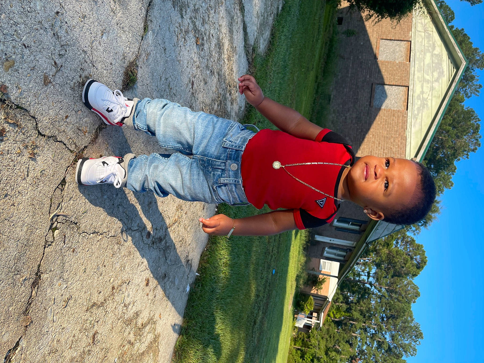 Sevyn is registered to the contest to win money with this photo: arm, concrete, denim, elbow, electric_blue, fun, grass, happy, human_leg, leisure, outdoor_shoe, people_in_nature, person, plant, recreation, shadow, sky, soil, toddler, tree