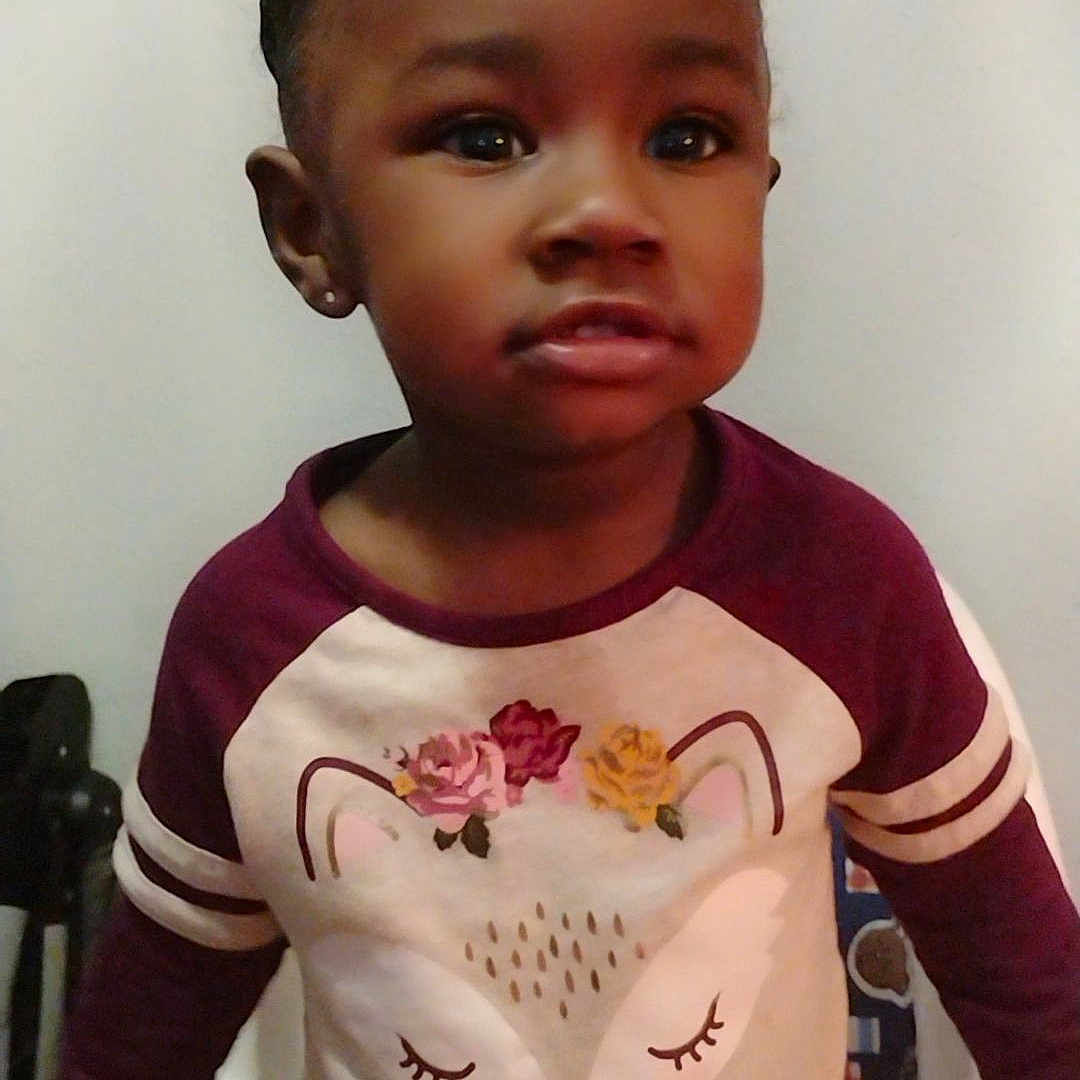 Rayelle is registered to the contest to win money with this photo: accessories, baby, clothing, cushion, dress, face, furniture, happy, head, homedecor, indoors, longsleeve, person, photography, portrait, shirt, sitting, sleeve, smile, t_shirt