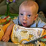 baby, child, blue_eyes, bib, giraffe_toy, plush_toy, playmat, curious, expression, indoor, soft_focus, colorful, cute, young_child, person, infant, clothing, face, smile, toddler