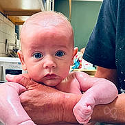 Oliver is registered to the contest to win money with this photo: baby, infant, child, person, skin, arms, bath, water, kitchen, hand, face, expression, curious, closeup, indoors, adult, holding, fresh, clean, towel