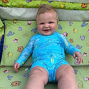 Kaiden is registered to the contest to win money with this photo: baby, child, smile, blue_swimsuit, sitting, animal_pattern, baby_seat, happy, cute, chubby, infant, face, skin, hand, foot, leg, indoors, patterned_fabric, colorful, portrait