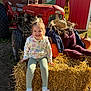 child, girl, smiling, hay_bale, tractor, pumpkin, scarecrow, straw_hat, outdoor, farm, fall, autumn, sunlight, clothing, footwear, nature, ground, agriculture, person, rural