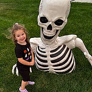 Kenzie joined the competition — help win amazing prizes! child, girl, smiling, grass, outdoor, skeleton, halloween, decoration, costume, black_tshirt, purple_shoes, toy, greenery, yard, holiday, fun, cute, playful, happy, posing