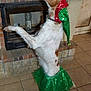 dog, pet, costume, holiday, elf_hat, green_skirt, indoor, fireplace, tile_floor, brown_and_white, standing, festive, cute, decor, water_bottle, attention, animal, pose, celebration, home