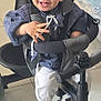 toddler, child, tricycle, smiling, indoors, striped_clothing, blue_shirt, white_pants, blue_sandals, seat, floor, playful, happy, face, hands, footwear, toy, baby, person, casual
