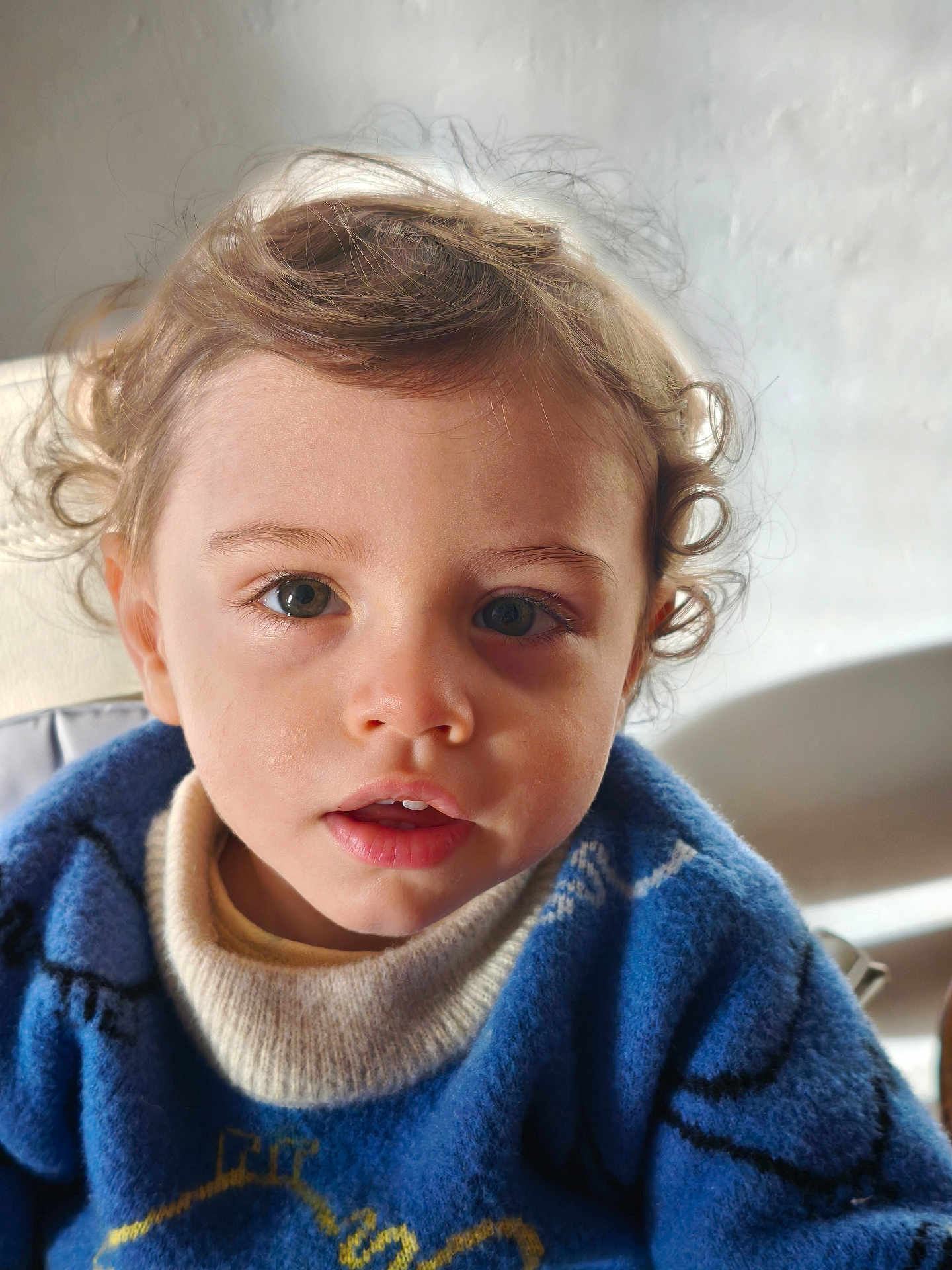 Adam Aaron Cooper participe au concours pour gagner de l'argent avec cette photo : baby, blue_sweater, casual_clothing, child, closeup, cozy, curiosity, curly_hair, cute, expression, eyes, face, indoors, natural_light, person, portrait, smiling, soft_light, toddler, young_child