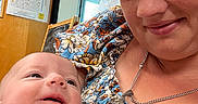 Abigail joined the competition — help win amazing prizes! baby, woman, smile, indoor, portrait, floral_dress, cross_necklace, door, window, blinds, holding, closeup, person, face, happy, infant, child, casual_clothing, expression, family
