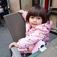 Maélya a rejoint le concours — aidez-le/la à gagner de superbes lots ! casual_clothing, chair, child, cute, daylight, metal_floor, outdoor, pacifier, person, pink_jacket, playful, short_hair, sitting, smiling, table, toddler, tongue_out, white_shoes, wooden_table, young_child