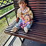 Maélya participe au concours pour gagner de l'argent avec cette photo : bench, child, clothing, daylight, doll, fence, greenery, hair_tie, jacket, jeans, outdoor, pacifier, person, portrait, shadow, sitting, sunlight, toddler, toy, wooden_bench