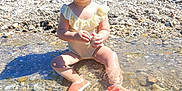Maélya a rejoint le concours — aidez-le/la à gagner de superbes lots ! baby, cap, child, exploring, greenery, happy, nature, outdoor, playing, rock, rocks, shoes, sitting, stream, summer, sunlight, swimsuit, toddler, water, water_ripples