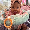 baby, child, infant, smiling, happy, portrait, bow, headband, activity_seat, baby_toy, teething_ring, colorful, pink, indoor, bedroom, seated, face, eyes, clothing, playtime