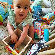 Lison participe au concours pour gagner de l'argent avec cette photo : baby, child, toy, wooden_box, plush_toy, stuffed_animal, play_mat, floor, indoor, curious, striped_clothing, octopus_toy, giraffe_toy, colorful, playtime, infant, hand, face, expression, crawling