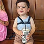 toddler, child, drink, cup, bench, wooden_bench, sitting, smiling, harness, shorts, tank_top, patterned_shorts, drink_cup, cow_print, happy, daylight, portrait, face, person, casual_clothing