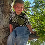 Nolan is registered to the contest to win money with this photo: child, boy, tree, branch, leaves, greenery, outdoor, nature, casual_clothing, jeans, crocs, smile, sunlight, daylight, park, young, portrait, happy, playful, tree_climbing