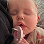 baby, sleeping, pacifier, face, hand, clothing, heart_pattern, closeup, infant, cozy, rest, child, soft_texture, skin, indoor, peaceful, toddler, cute, portrait, relaxation