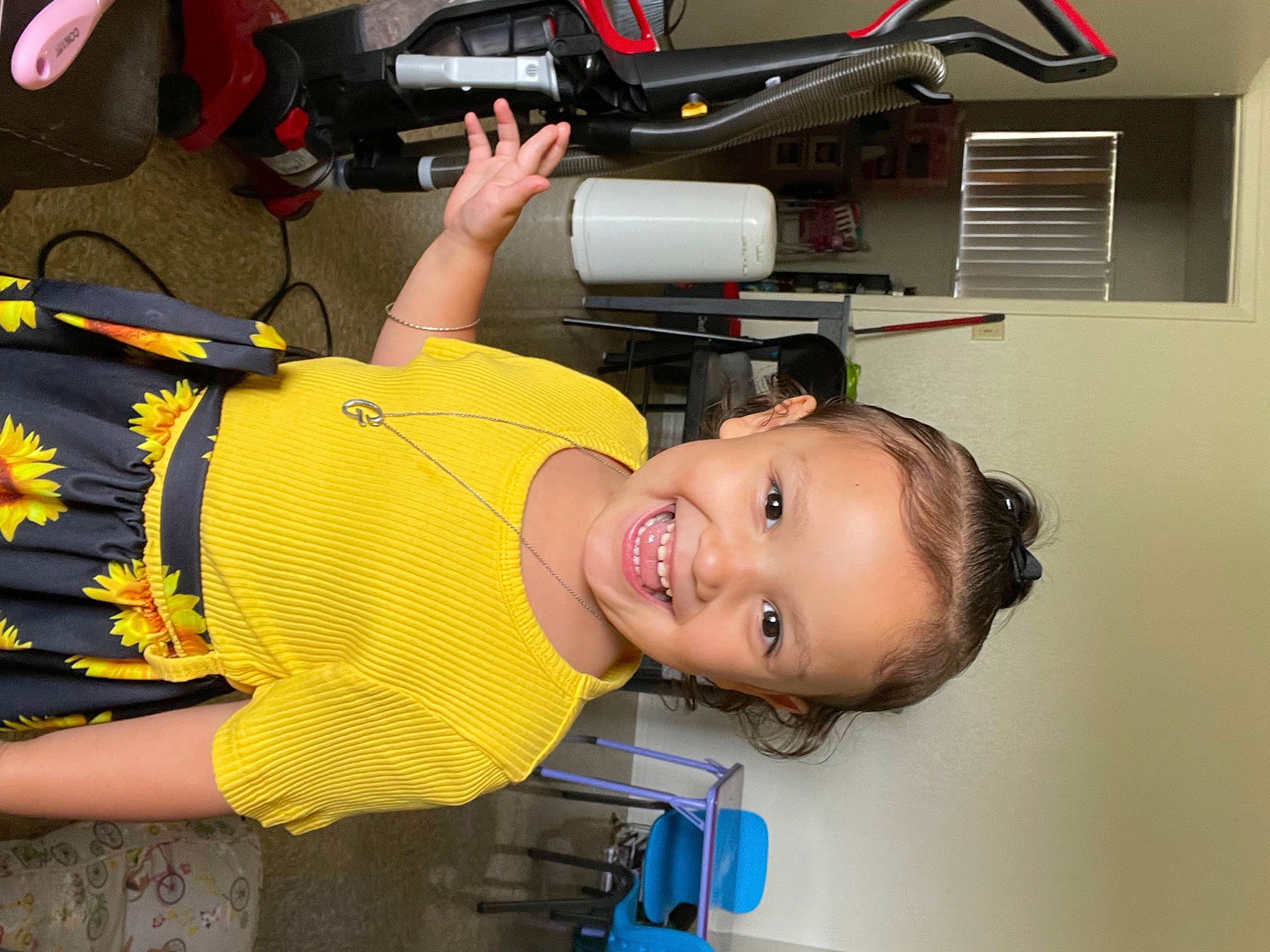 Gabriella is registered to the contest to win money with this photo: baby_products, baby_toddler_clothing, bag, child, fun, happy, joy, luggage_and_bags, person, room, smile, t_shirt, thigh, toddler, yellow