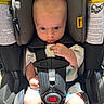 baby, car_seat, infant, child, safety_harness, seat_belt, cute, indoors, sunlight, shadow, clothing, person, seat, head_support, young_child, infant_clothing, baby_face, small_hands, car_interior, curious_expression
