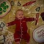 baby, pajamas, cookie_cutters, cookies, baking_tools, whisk, rolling_pin, holiday_plate, flour, happy, smiling, floor, festive, red_clothing, chocolate_cookies, icing, gingerbread_wrappers, infant, indoors, celebration