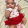 baby, smiling, infant, tutu, pink, red, headband, mittens, socks, cherry_pattern, cute, lying_down, blanket, happy, child, portrait, soft_lighting, clothing, person, adorable