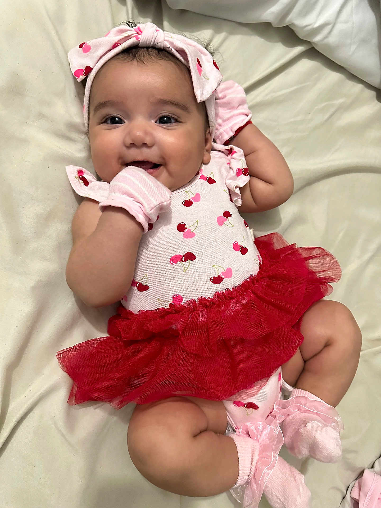 Hazel joined the competition — help win amazing prizes! baby, smiling, infant, tutu, pink, red, headband, mittens, socks, cherry_pattern, cute, lying_down, blanket, happy, child, portrait, soft_lighting, clothing, person, adorable