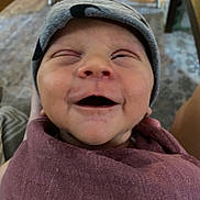 Rowen joined the competition — help win amazing prizes! baby, smile, face, infant, blanket, beanie, clothing, happy, indoor, person, headwear, wrapped, cute, skin, portrait, newborn, expression, child, human, sitting