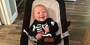 Mason joined the competition — help win amazing prizes! baby, smiling, skeleton_outfit, baby_rocker, indoor, wooden_floor, happy, clothing, infant, person, seat, casual, home, cute, child, footwear, sock, black, white, comfort