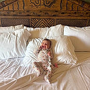 Jaylyn joined the competition — help win amazing prizes! baby, bed, carved_wood, child, comfort, cozy, cute, floral_onesie, furniture, happy, indoor, infant, pillow, portrait, resting, sleepwear, smiling, white_bedding, wooden_headboard, young_child