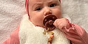 Lila participe au concours pour gagner de l'argent avec cette photo : baby, infant, pacifier, headband, pink_clothing, white_vest, soft_texture, blanket, closeup, portrait, child, cute, adorable, indoor, person, face, hand, expression, laying, young
