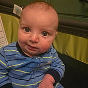 Tyler is registered to the contest to win money with this photo: baby, blue_clothing, cheeks, child, chubby_cheeks, close_up, curious_expression, eyes, face, fist, hands, home_interior, indoor, infant, nursery, onesie, playpen, portrait, striped_clothing, warm_lighting