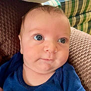 Tyler joined the competition — help win amazing prizes! baby, infant, face, eyes, blue_clothing, cushion, plaid_background, closeup, skin, expression, head, person, indoors, newborn, portrait, child, young, resting, soft_texture, curious