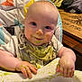 baby, high_chair, messy, food, green_food, bib, smiling, face, hands, indoor, wooden_table, clothing, cheeky, feeding_time, child, infant, cute, portrait, happy, home