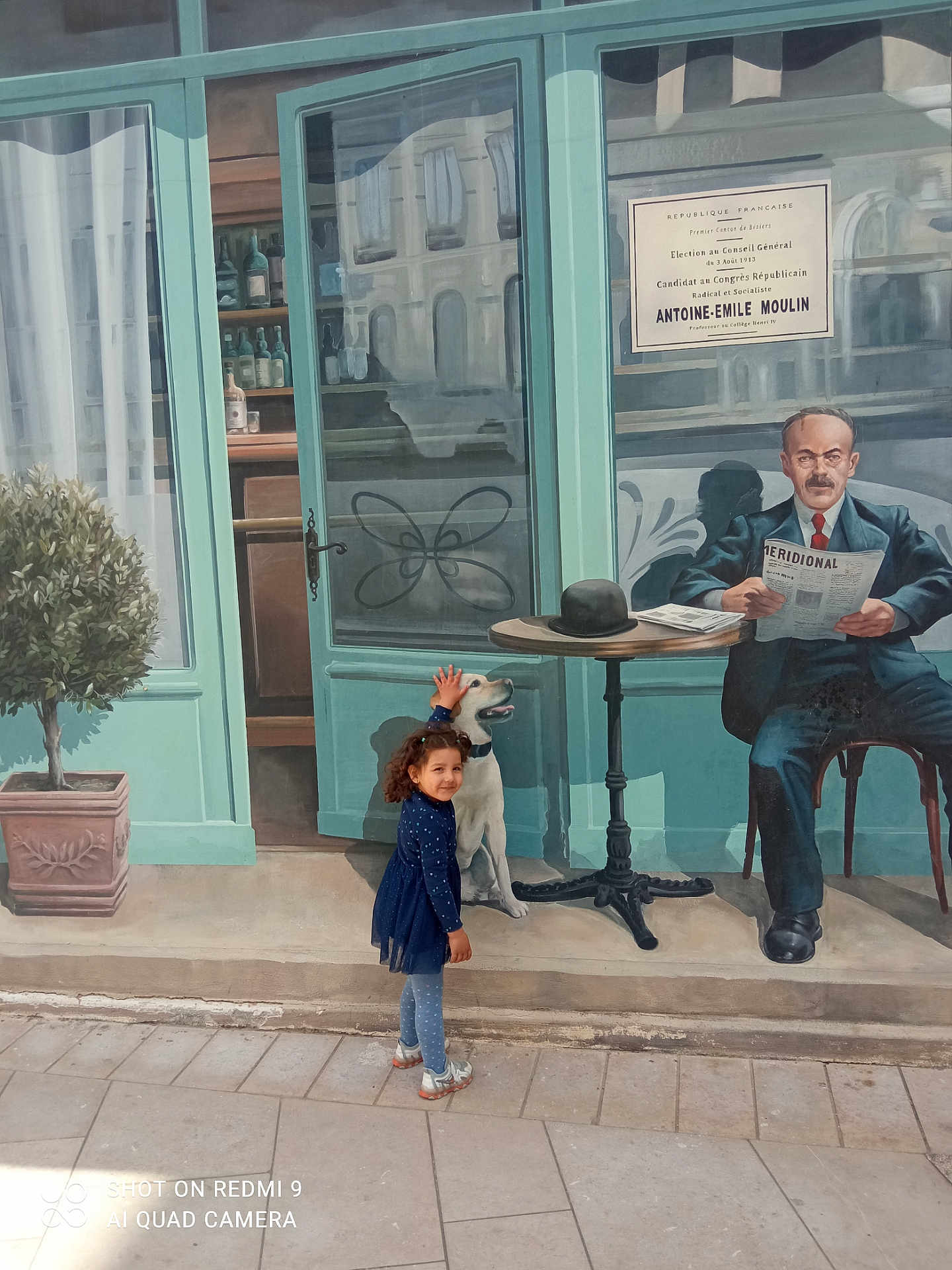 Norsine a rejoint le concours — aidez-le/la à gagner de superbes lots ! child, girl, mural, street_art, dog, painting, outdoor, pavement, tree, table, man, newspaper, hat, window, door, curtain, building, smile, blue_dress, shoes