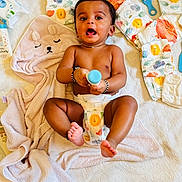 Krithin is registered to the contest to win money with this photo: baby, diaper, blanket, baby_bottle, brush, child, infant, cute, smiling, lying_down, nursery, soft_texture, animal_print, bear_face, colorful, playful, happy, skin, bracelet, toddler