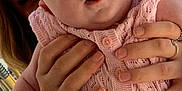 Tallulah is registered to the contest to win money with this photo: adult, baby, background, casual, closeup, curious, daylight, expression, face, glasses, hands, holding, infant, knitwear, outdoor, person, pink_clothing, portrait, seated, skin