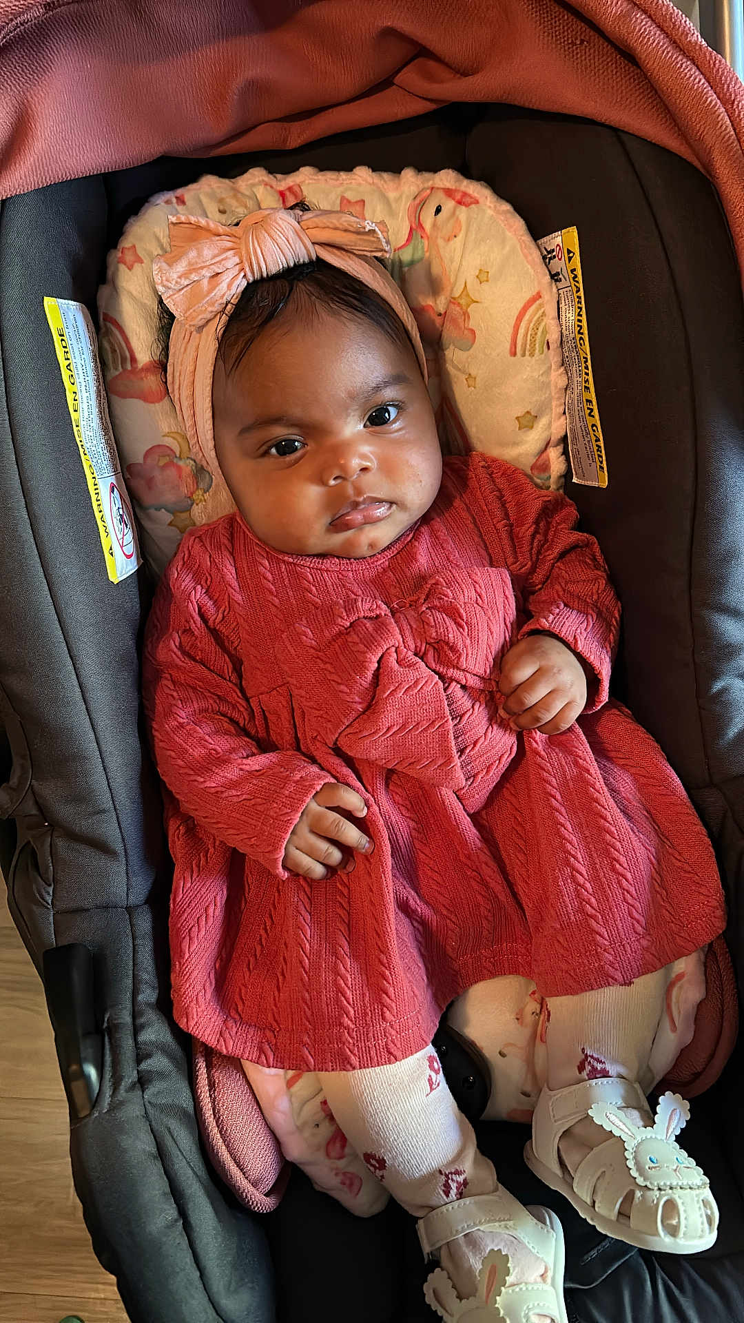 Meret joined the competition — help win amazing prizes! baby, infant, car_seat, pink_dress, headband, tights, sandals, bunny_design, cushion, face, hand, footwear, child, indoors, floor, patterned_clothing, cute, portrait, seated, clothing