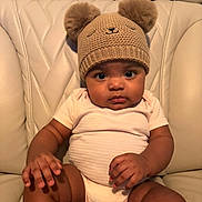 Meret is registered to the contest to win money with this photo: baby, infant, cute, hat, knit_hat, bear_ears, leather_couch, seated, chubby_cheeks, curious_eyes, onesie, socks, indoor, portrait, child, soft_lighting, skin, hands, legs, comfortable