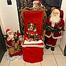 dog, christmas, holiday, santa_claus, red, decorations, throne, indoor, festive, reindeer, tile_floor, small_dog, costume, plush, figurines, white_beard, chair, celebration, festivity, seasonal