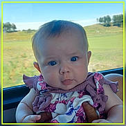 Sadie-Mae joined the competition — help win amazing prizes! baby, infant, child, portrait, face, blue_eyes, curious, clothing, floral_pattern, purple, hands, car_interior, window, scenery, outdoor_view, nature, greenery, hill, daylight, cute