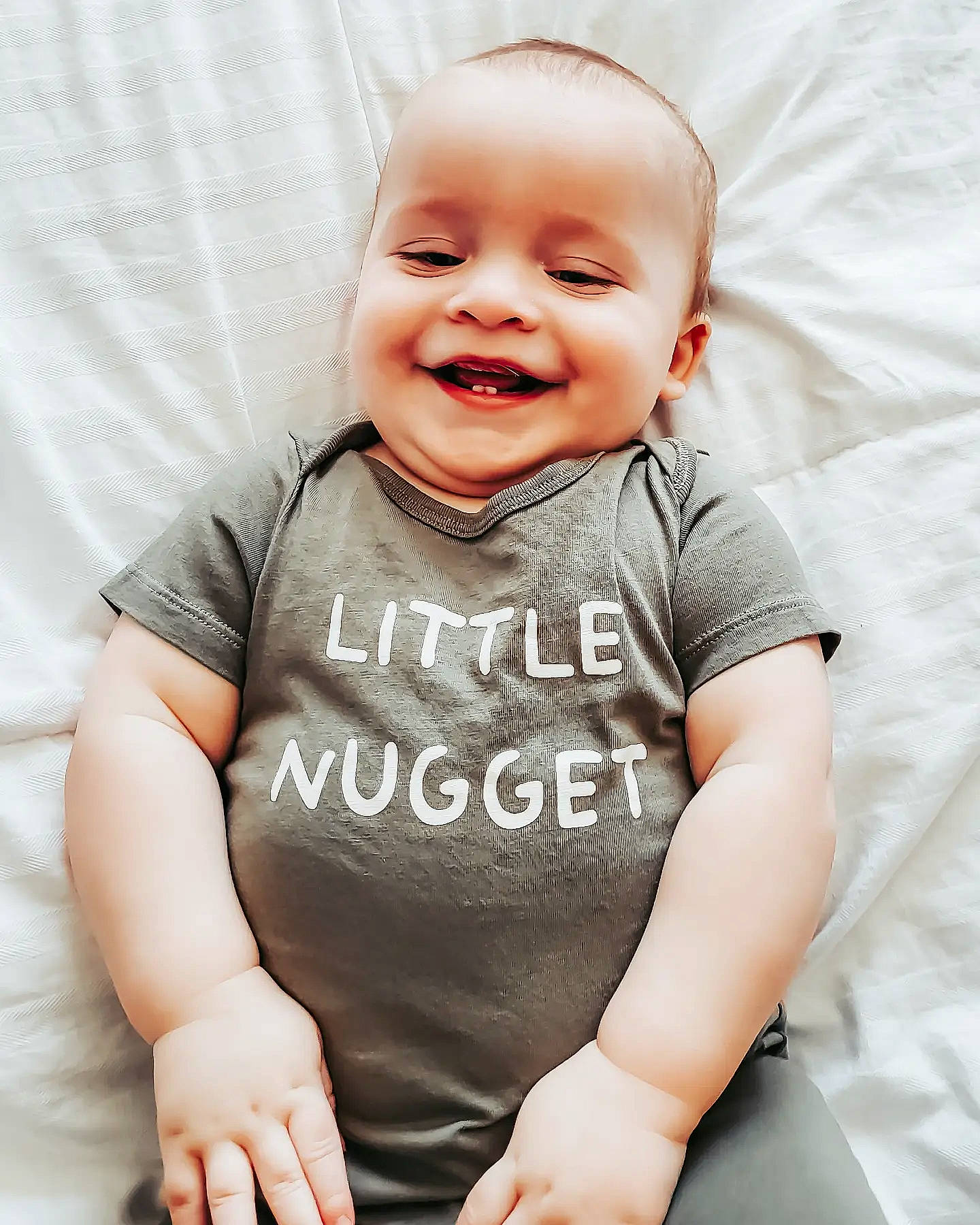 Daxon is registered to the contest to win money with this photo: arm, baby, baby_toddler_clothing, cheek, comfort, eye, face, finger, gesture, grey, hand, happy, head, human_body, joy, neck, person, product, sleeve, smile